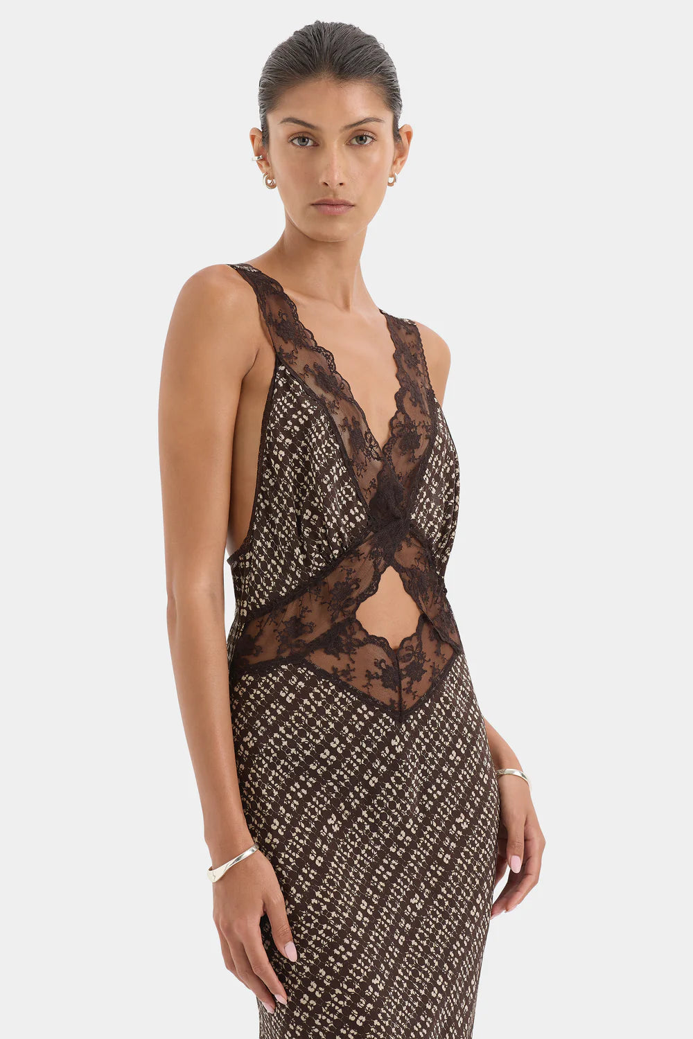 Woman wearing a patterned dress with lace detailing on a white background
