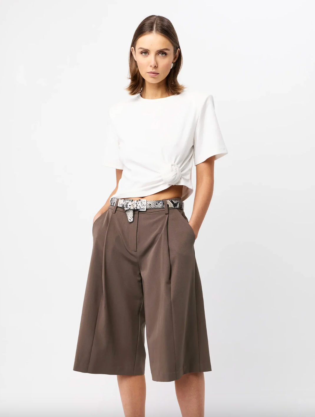 Woman wearing a white top and brown shorts on a white background