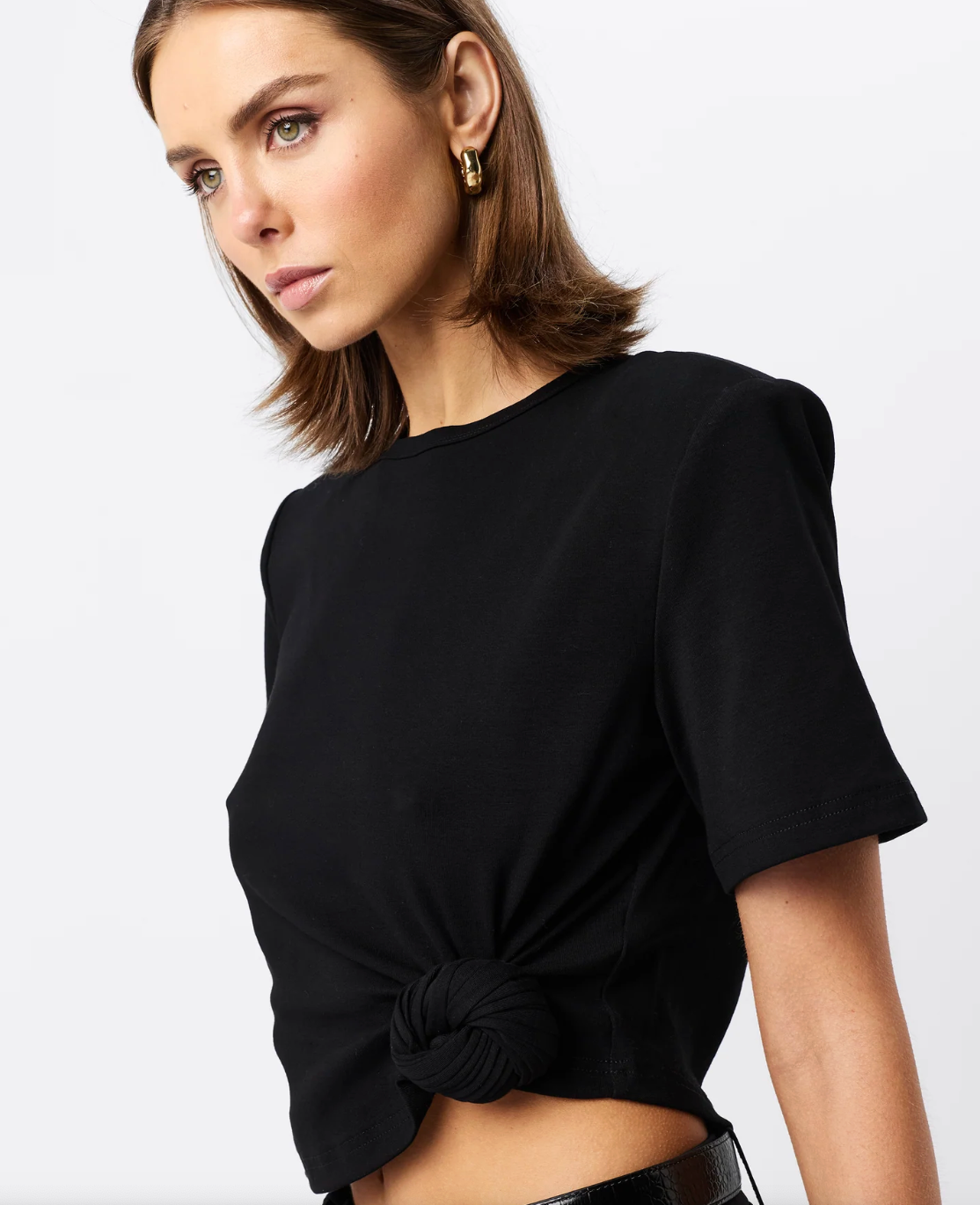 Woman wearing a black Fashion Tshirt with shoulder pads with a white background