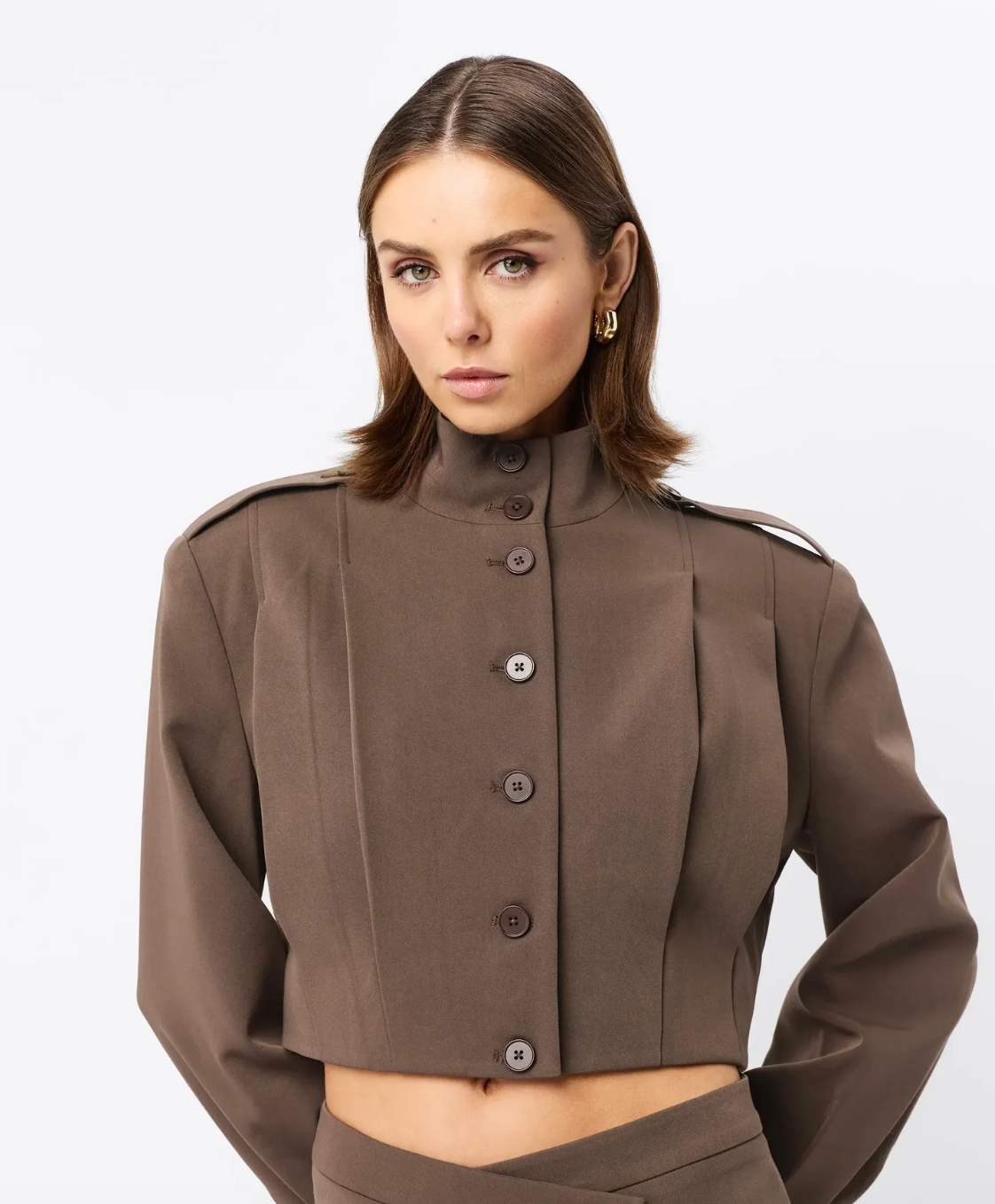 Woman wearing a brown jacket with button details on a white background