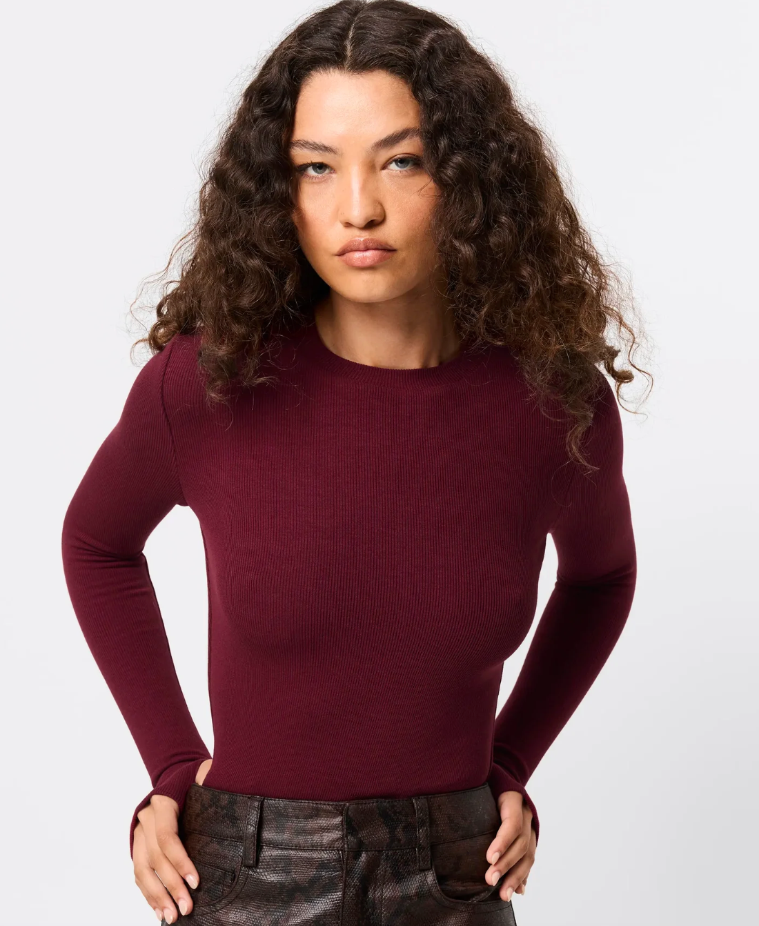 Woman wearing a maroon long-sleeve top against a white background
