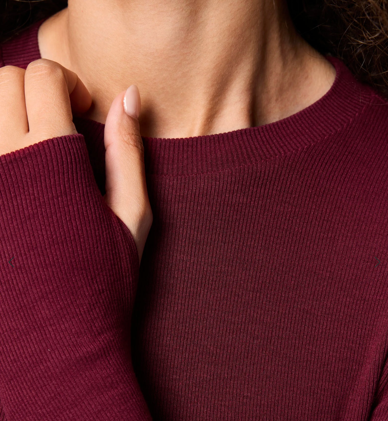 Close-up of a person wearing a maroon sweater with a neutral background