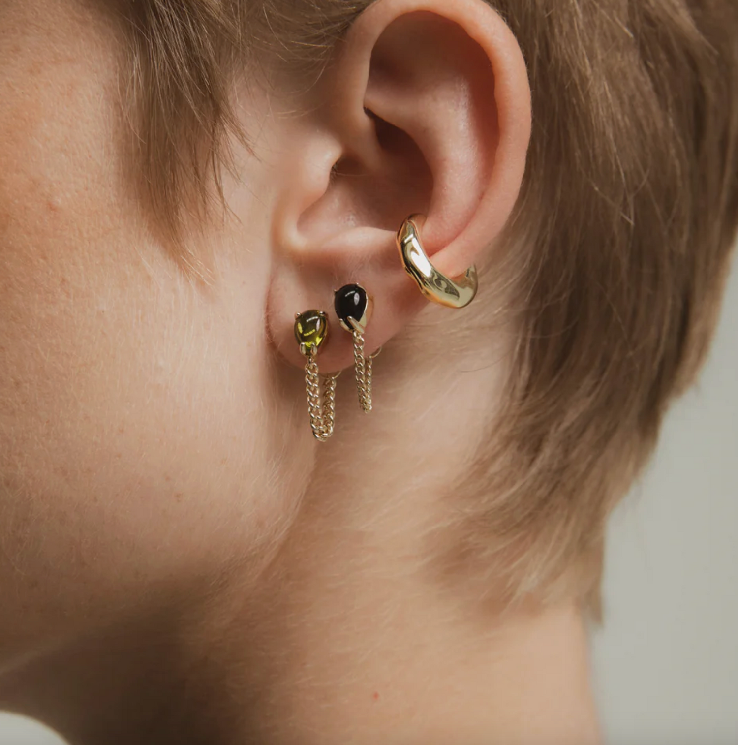 Close-up of an ear wearing gold hoop earrings with a blurred background