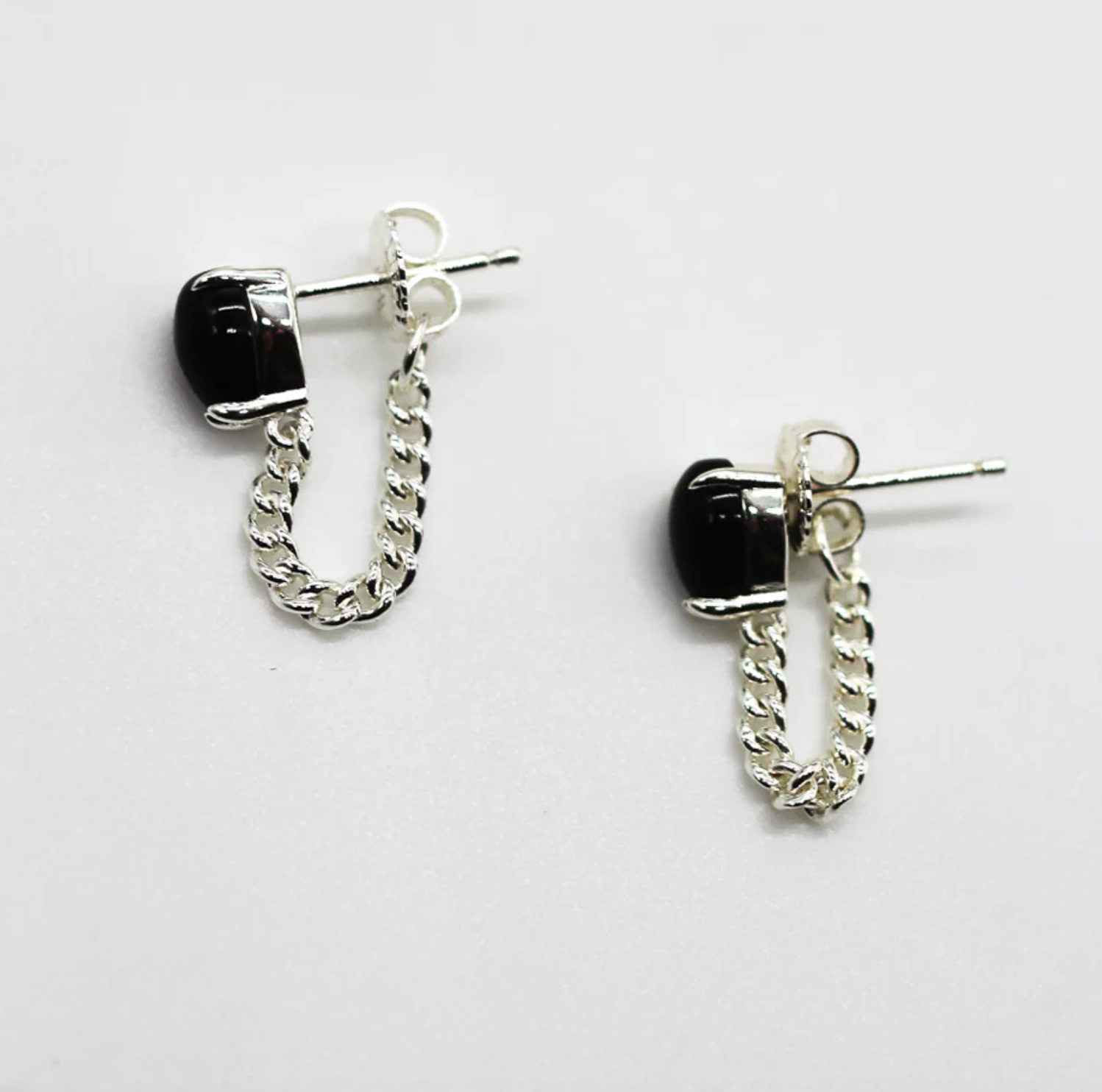 Pair of silver chain earrings with black beads on a white background