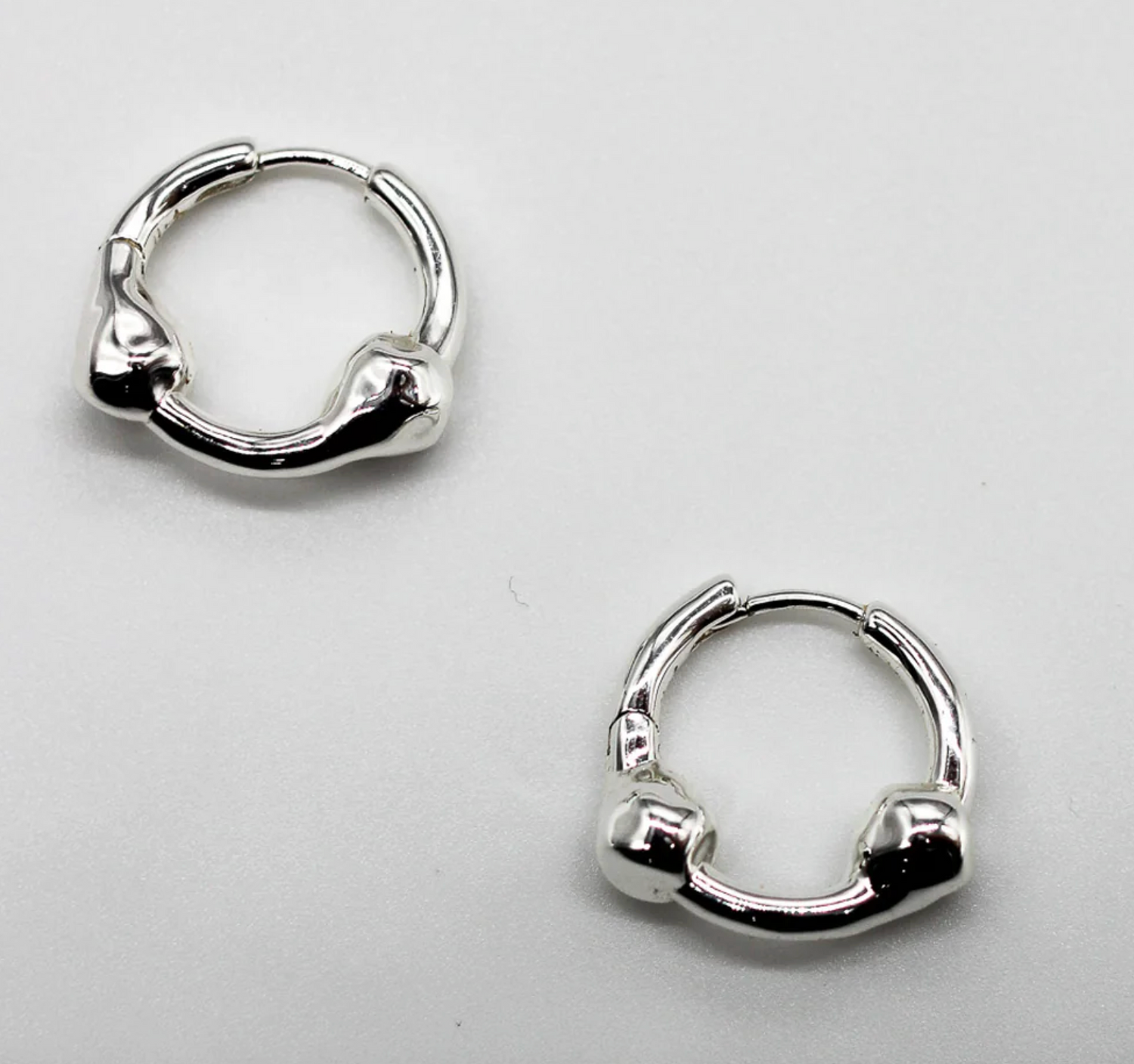 Pair of silver hoop earrings on a light gray background