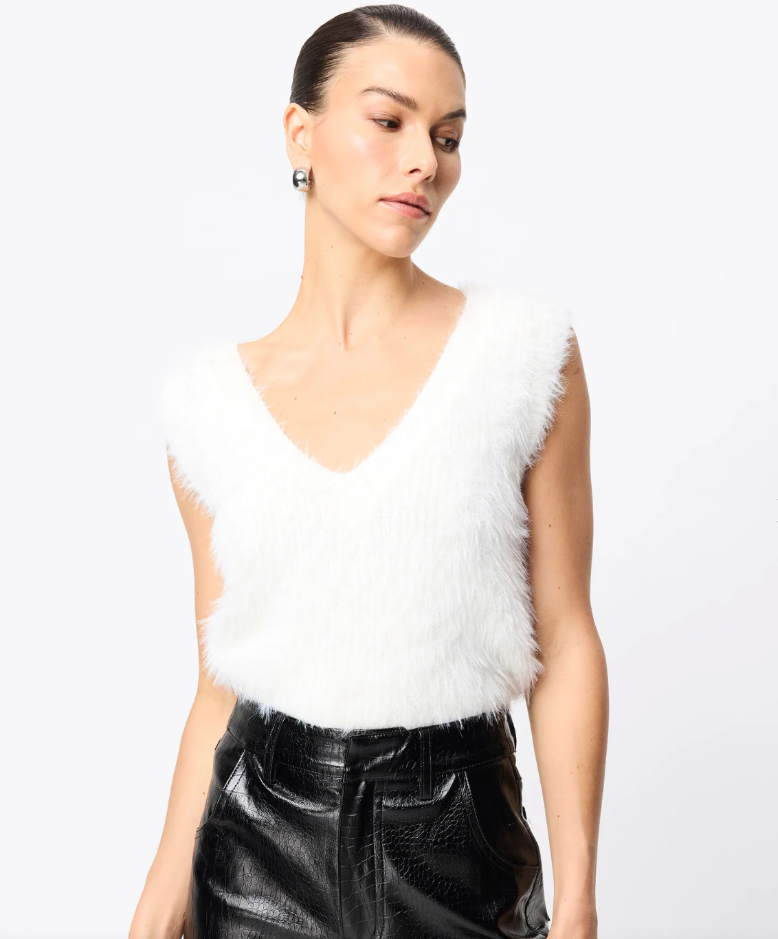Woman wearing a white fur vest over a black leather outfit on a white background