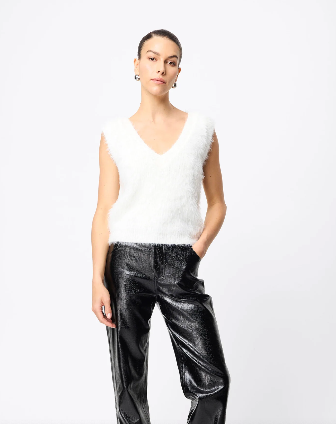 Woman wearing a white sleeveless top and black pants on a white background