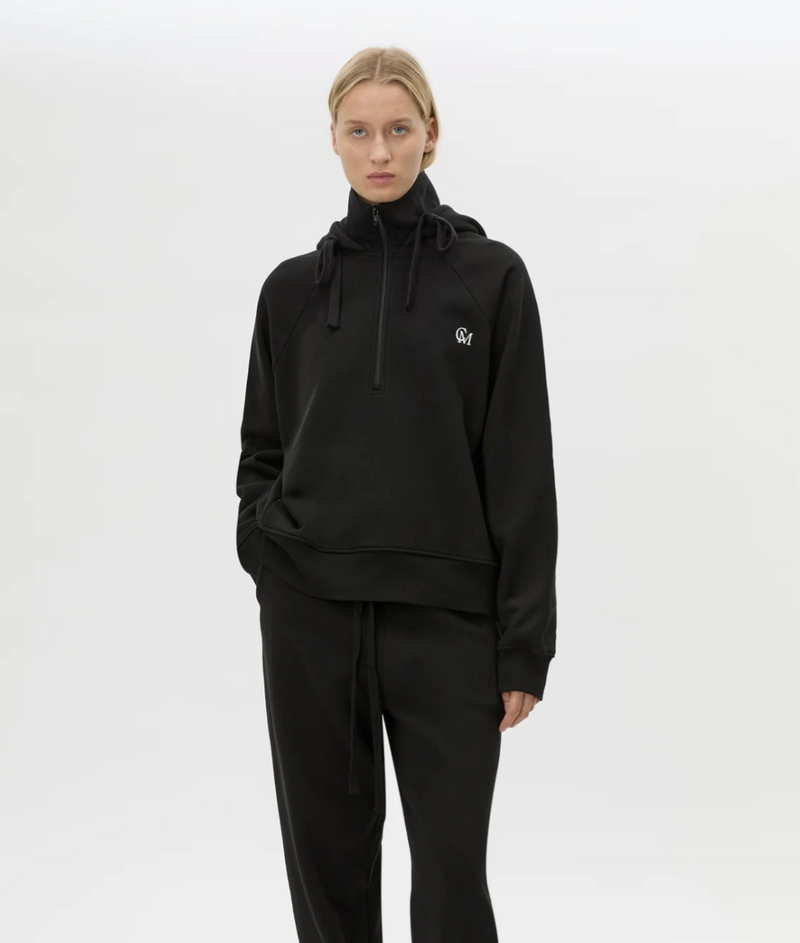 Person wearing a black hoodie with a logo on a white background