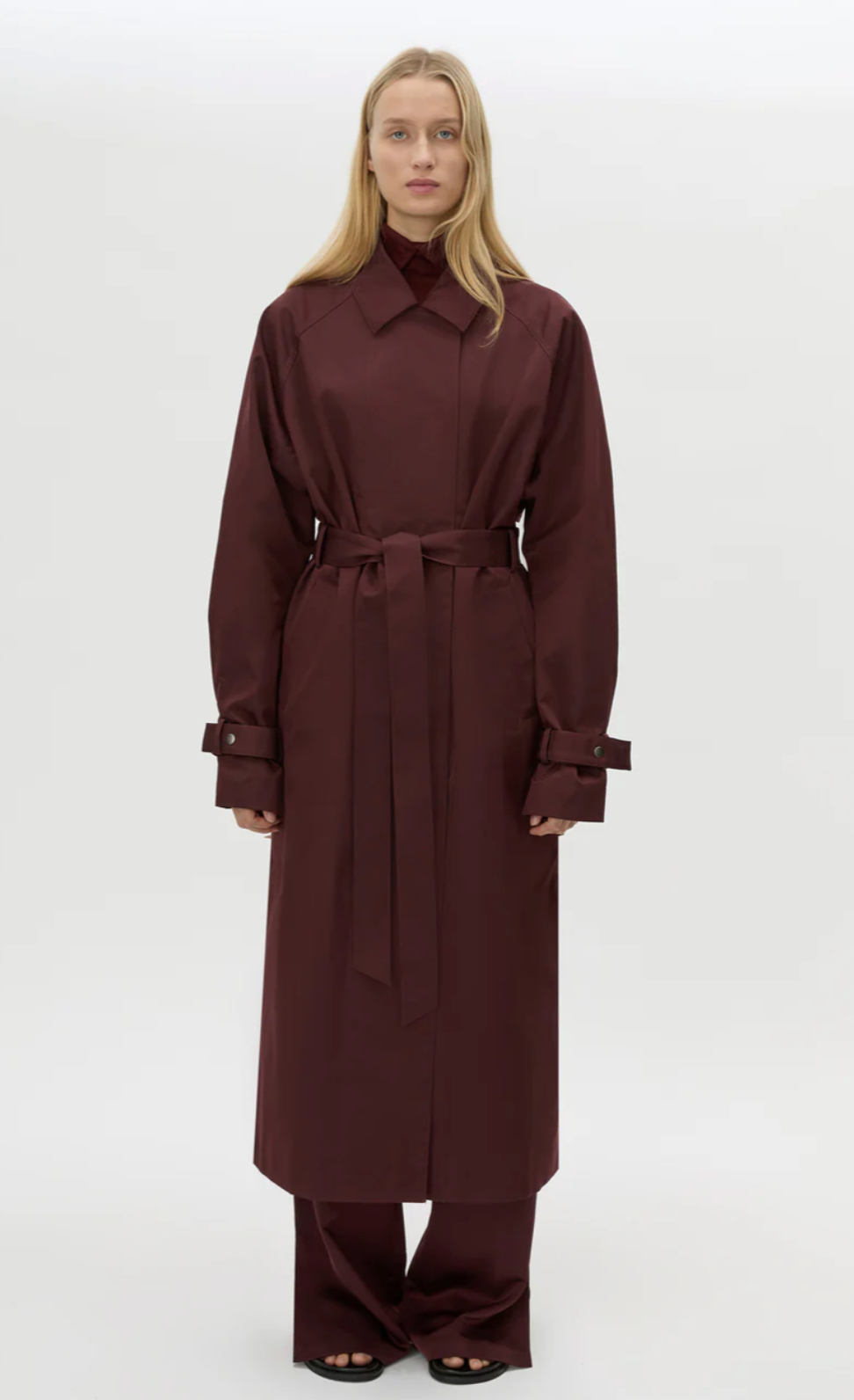 Woman wearing a long brown coat on a white background