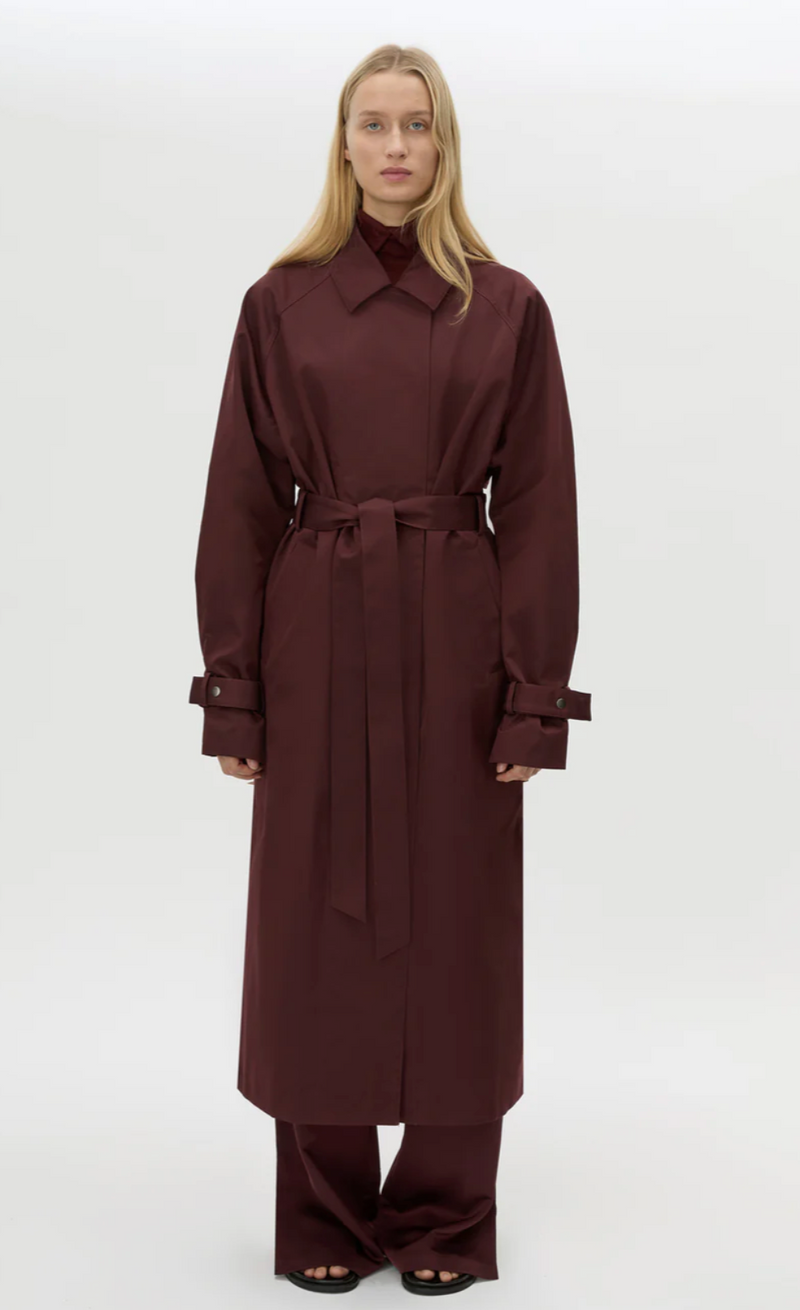 Woman wearing a long brown coat on a white background