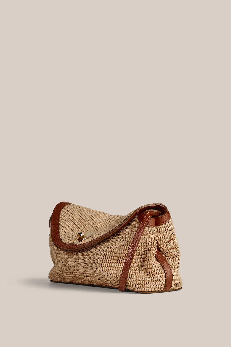 Woven handbag with brown leather accents on a beige background