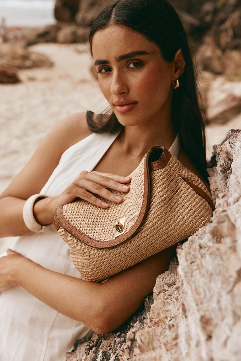 Woman holding a woven handbag in a natural setting