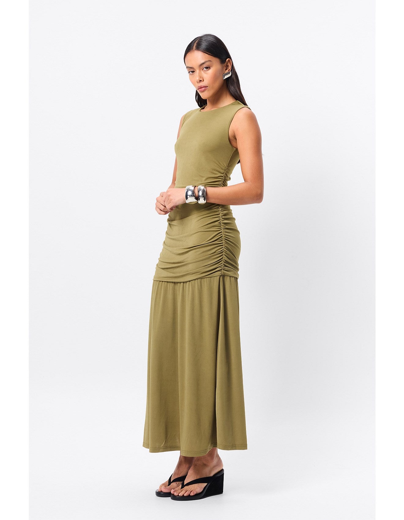 Woman standing in an olive dress for a special occasion.
Refined yet relaxed, the Sole Purpose Maxi Dress in Olive redefines everyday elegance. Designed in a soft stretch jersey fabrication, this sleeveless silhouette offers a round neckline and gathered detailing through the sides, sculpting the waist and hips for a flattering fit. The design falls to a gently flared maxi skirt, creating beautiful movement with every step. Body-lined for comfort, this dress is an effortless choice for both casual days and 