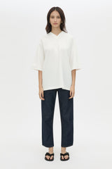 Woman wearing a white top and dark pants on a white background