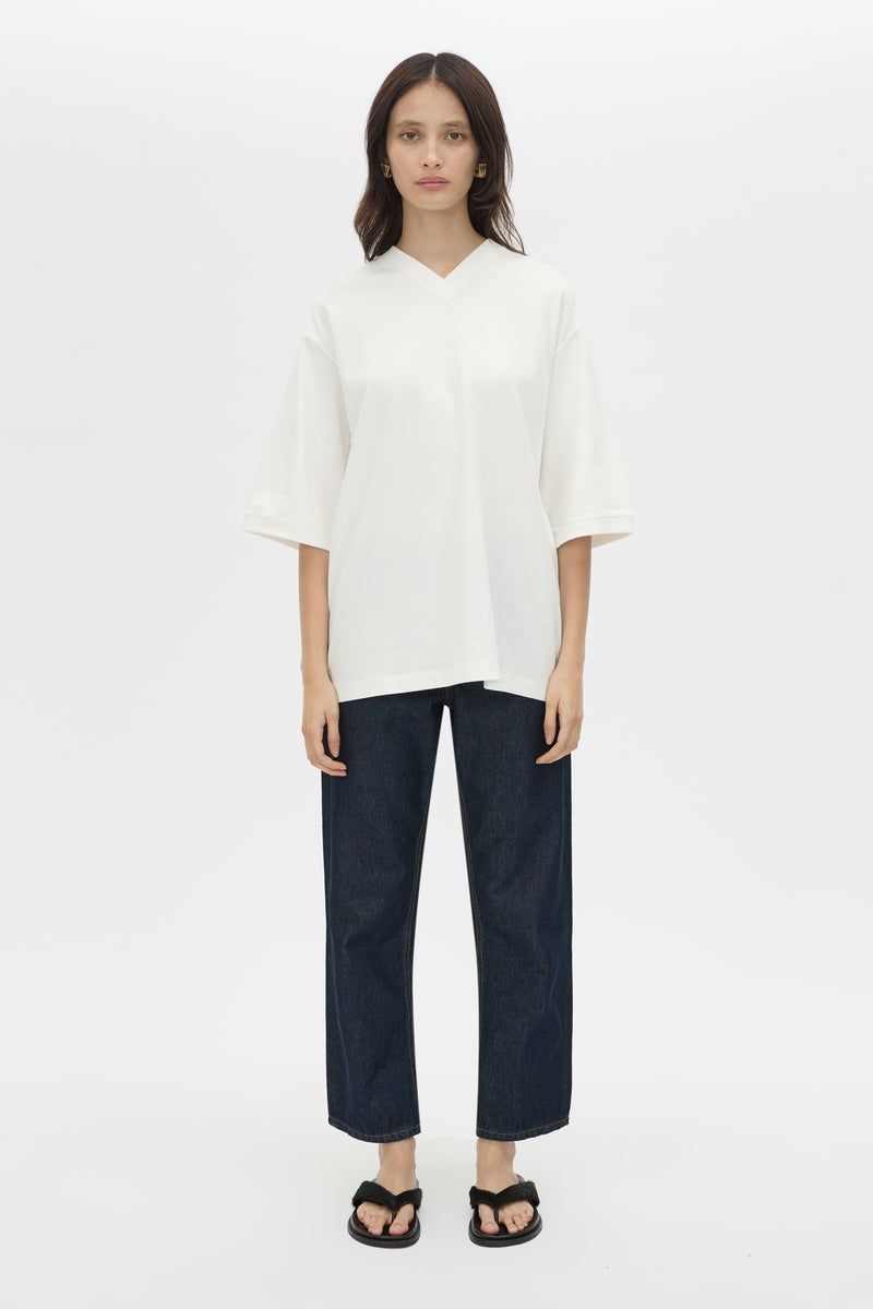 Woman wearing a white top and dark pants on a white background