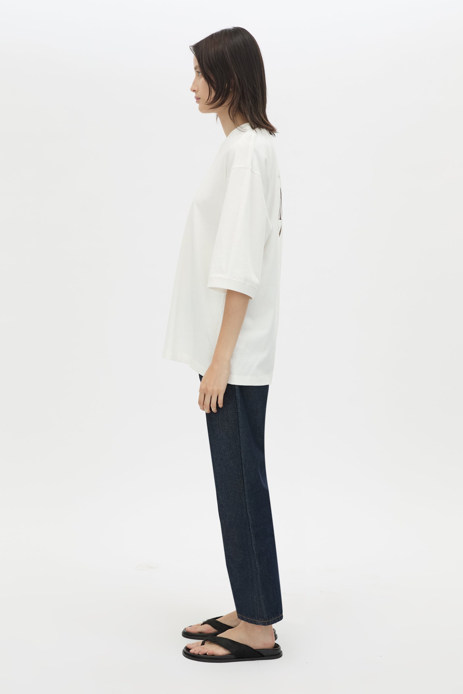 Person wearing a white shirt and dark pants on a white background