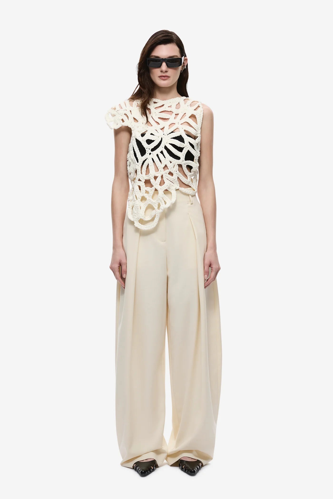 Model wearing a cream-colored outfit with a unique top design on a white background