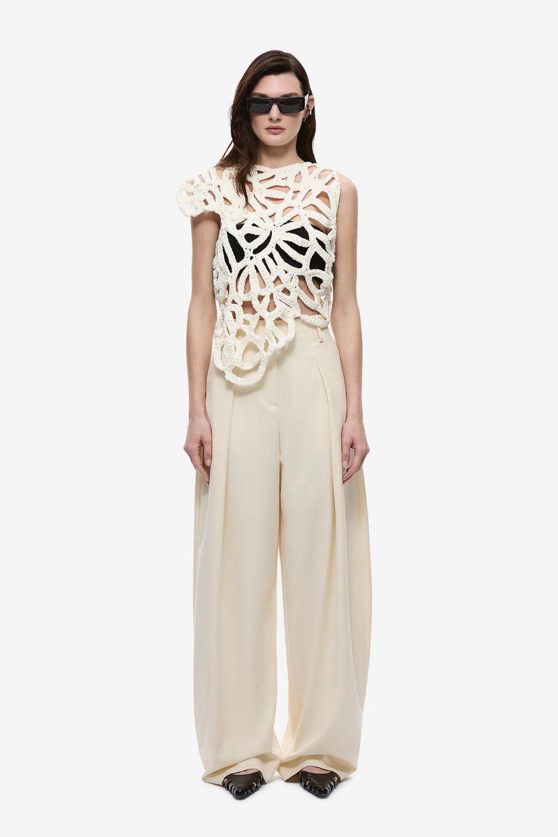 Model wearing a cream-colored outfit with a unique top design on a white background