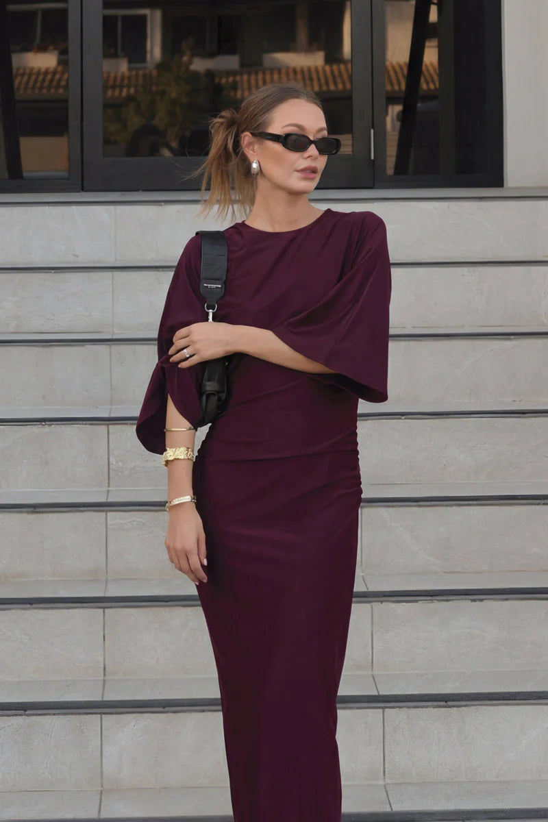 Woman in a burgundy outfit standing on steps with a blurred background