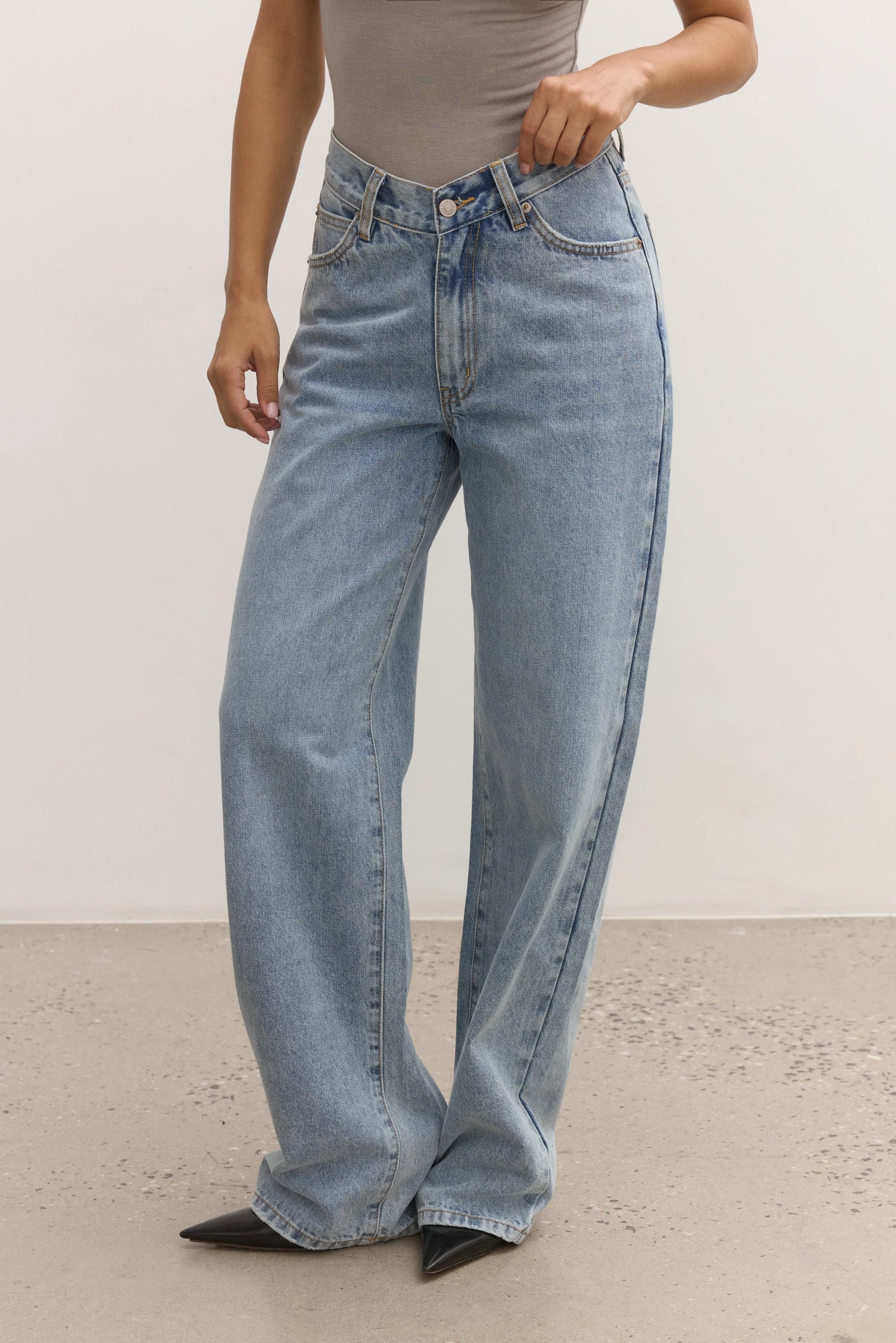 Person wearing light blue jeans on a plain background