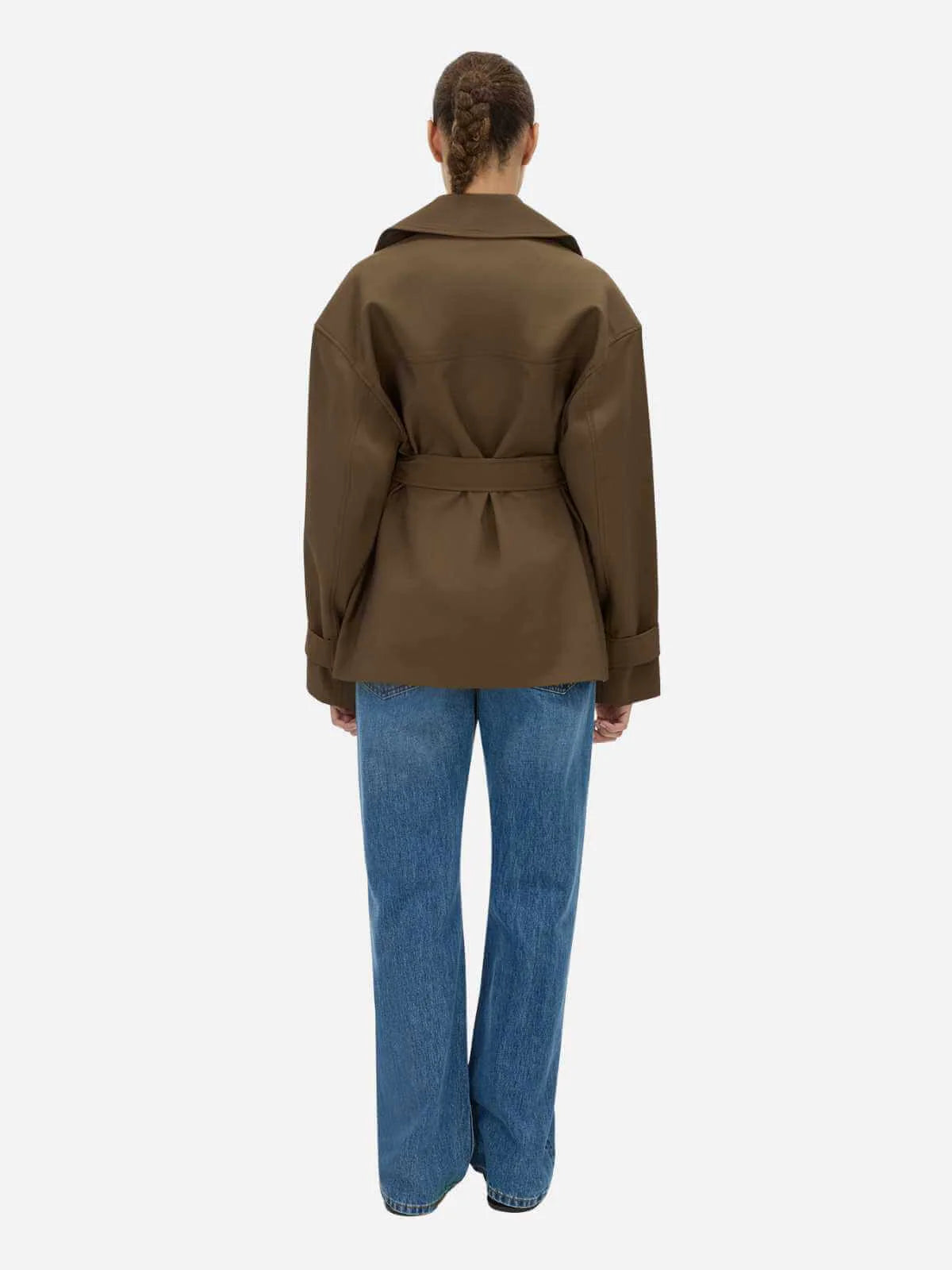 Person wearing a brown jacket and blue jeans on a white background