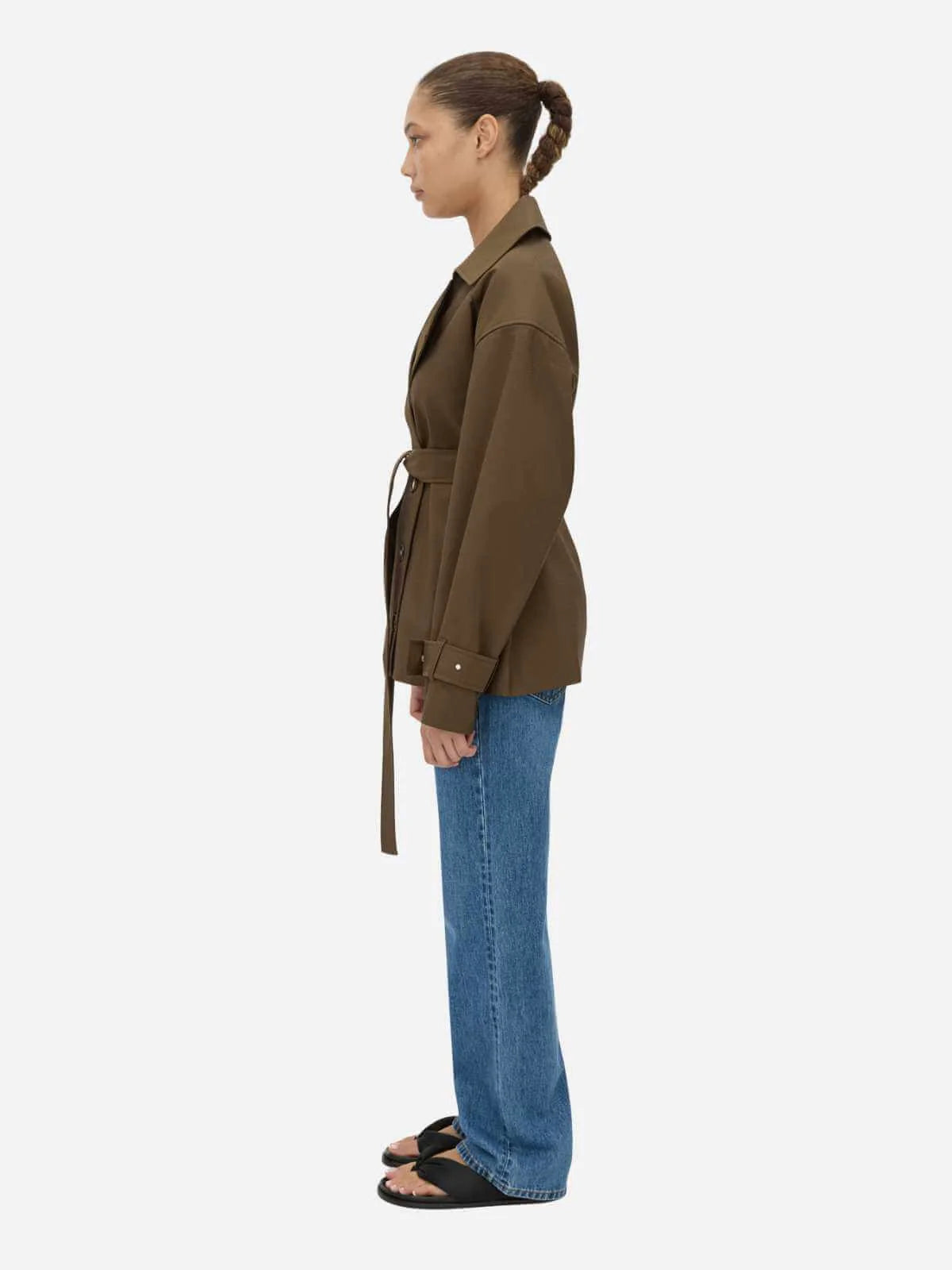 Woman wearing a brown jacket and blue jeans on a white background